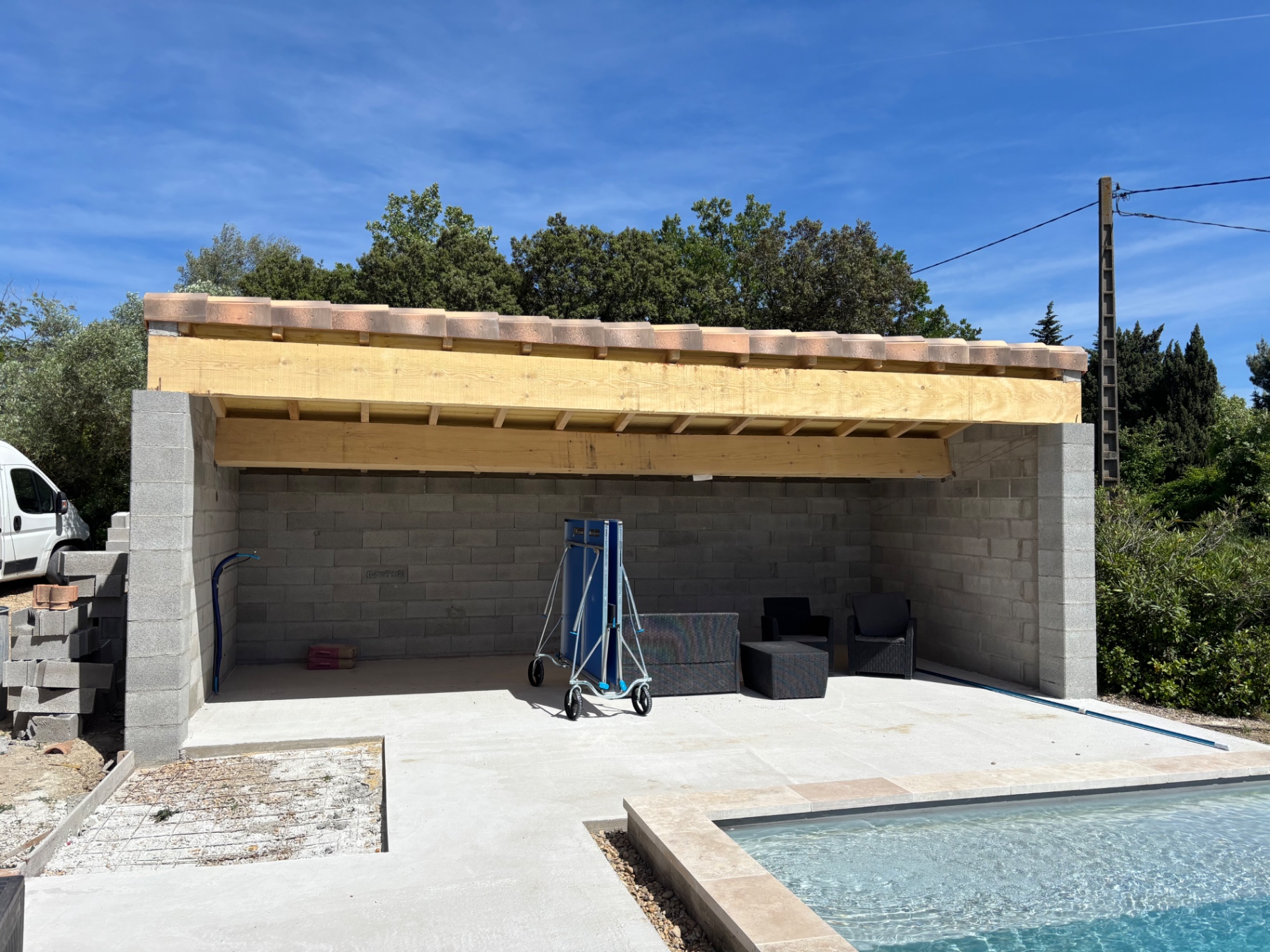 Pool house maçonné avec charpente bois et couverture en tuiles au bord de la piscine